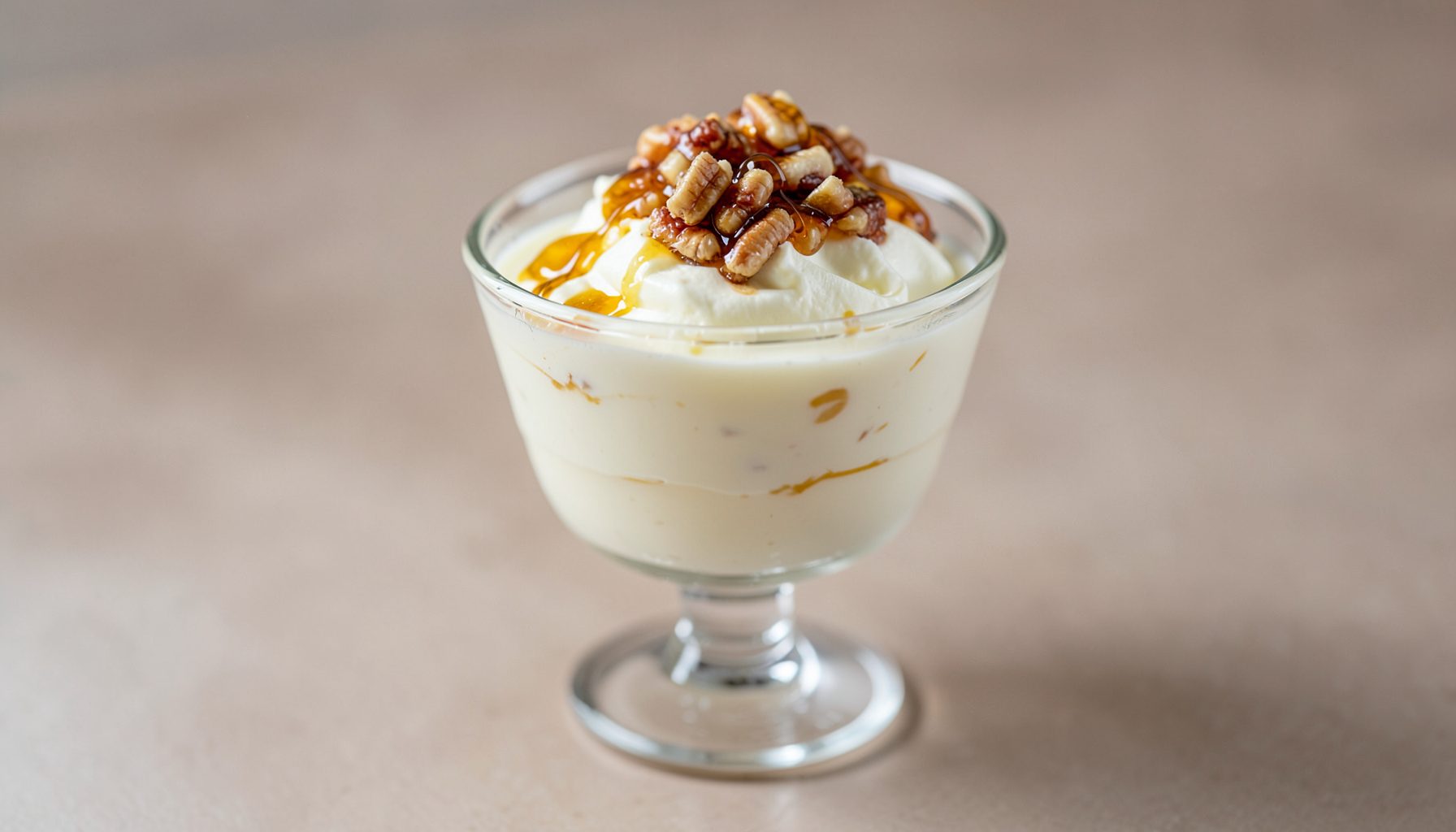 Mousse de queso de cabra en copas de cristal, coronada con nueces caramelizadas y un hilo de miel dorada.